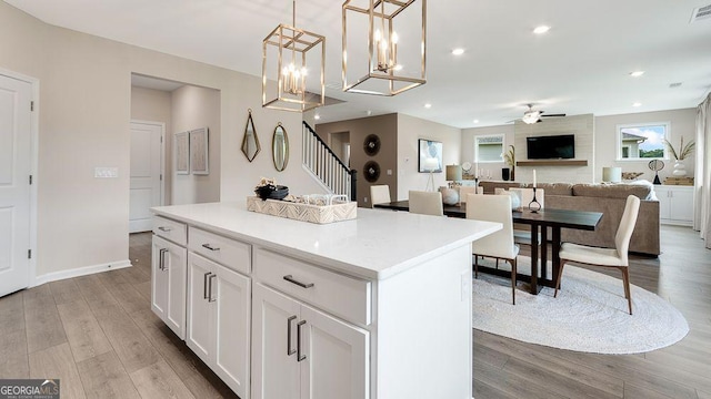 52 Sheryl Way, Loganville, GA 30052 - kitchen with a ceiling fan, a center island, wood finished floors, white cabinetry, and decorative light fixtures