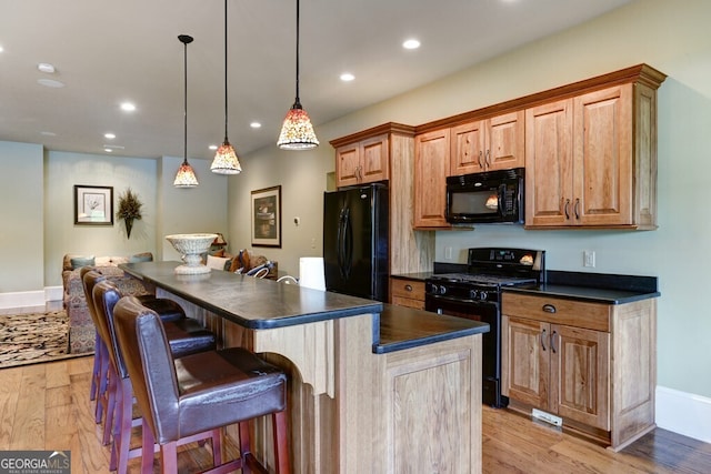 2373 Herman Drake Rd, Young Harris, GA 30582 - kitchen featuring a kitchen bar, a center island, dark countertops, light wood-style floors, and black appliances