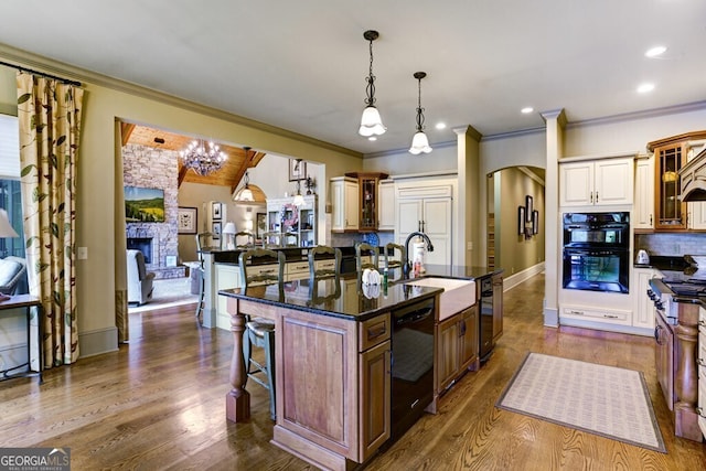 2373 Herman Drake Rd, Young Harris, GA 30582 - kitchen with an island with sink, a sink, a breakfast bar, glass insert cabinets, and black appliances