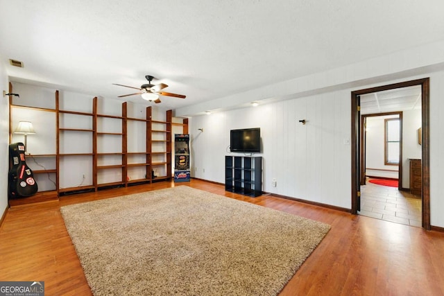 unfurnished living room featuring light wood-style flooring, visible vents, baseboard heating, and ceiling fan