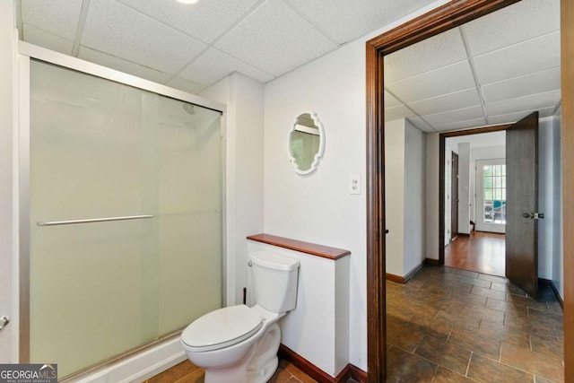 full bath with a drop ceiling, toilet, and a stall shower