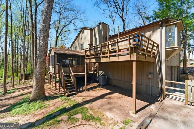 rear view of house with cooling unit, a sunroom, stairs, a deck, and a chimney
