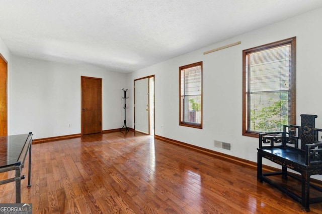 sitting room with hardwood / wood-style floors, plenty of natural light, baseboards, and visible vents
