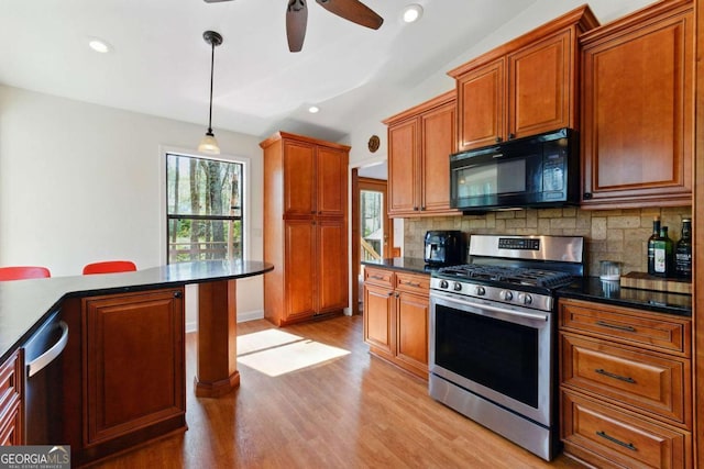 kitchen with a ceiling fan, backsplash, hanging light fixtures, light wood-style flooring, and appliances with stainless steel finishes