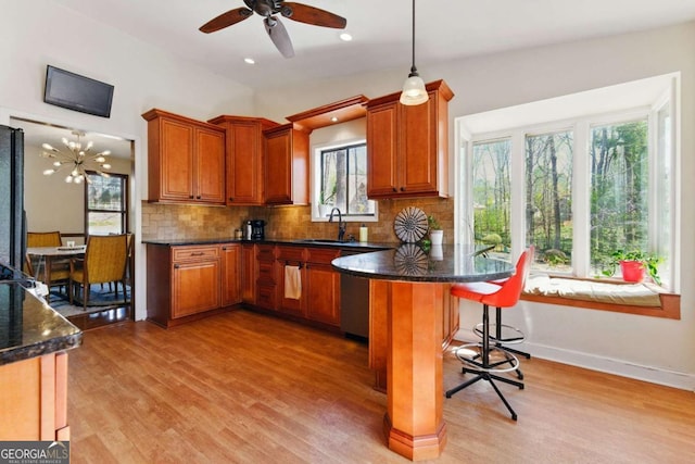 kitchen featuring a healthy amount of sunlight, light wood-type flooring, decorative backsplash, a sink, and brown cabinetry