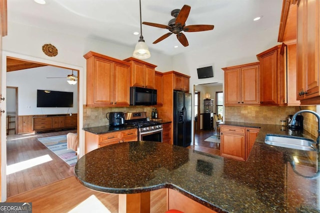 kitchen featuring black appliances, wood finished floors, ceiling fan, and a sink