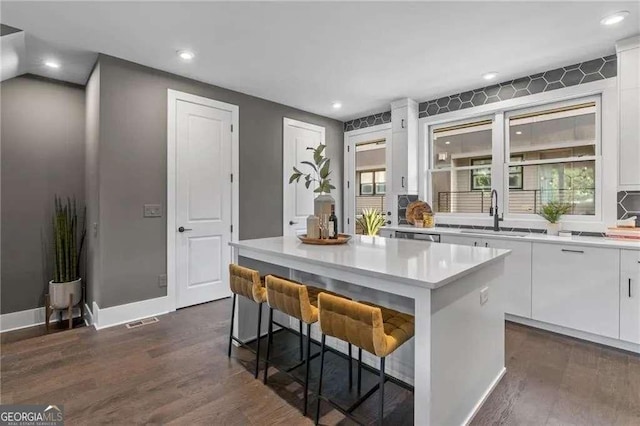 kitchen featuring light countertops, dark wood-style floors, white cabinetry, and a sink