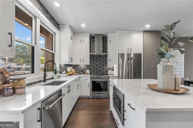 kitchen featuring wall chimney range hood, recessed lighting, a sink, stainless steel appliances, and decorative backsplash