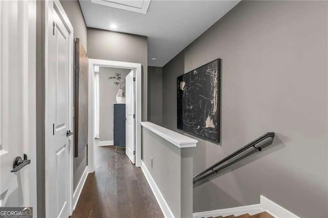 hall with baseboards, an upstairs landing, and dark wood finished floors