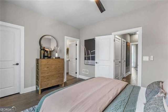 bedroom with visible vents, baseboards, a ceiling fan, ensuite bath, and wood finished floors