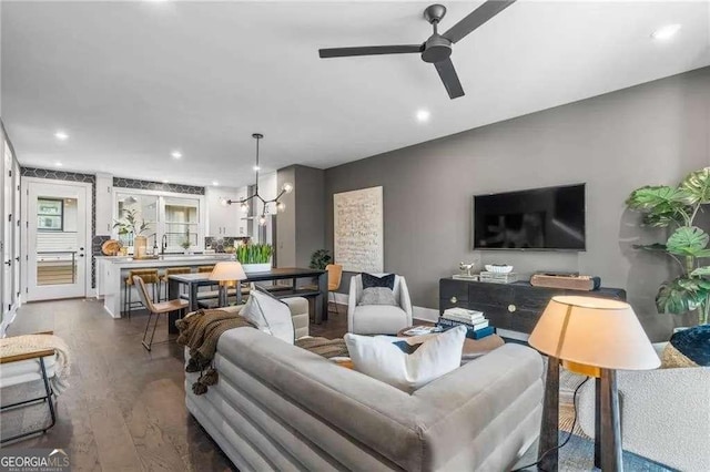 living area with ceiling fan with notable chandelier, dark wood-style floors, and recessed lighting
