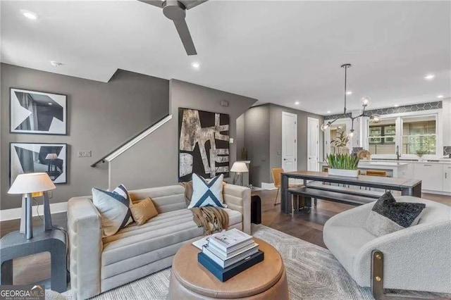 living room with recessed lighting, ceiling fan with notable chandelier, baseboards, and wood finished floors