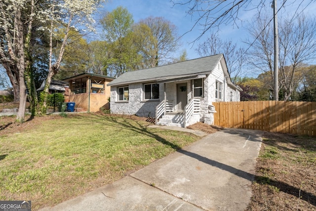 1441 Ezra Church Dr NW, Atlanta, GA 30314 - bungalow-style home featuring stone siding, a shingled roof, fence, and a front yard