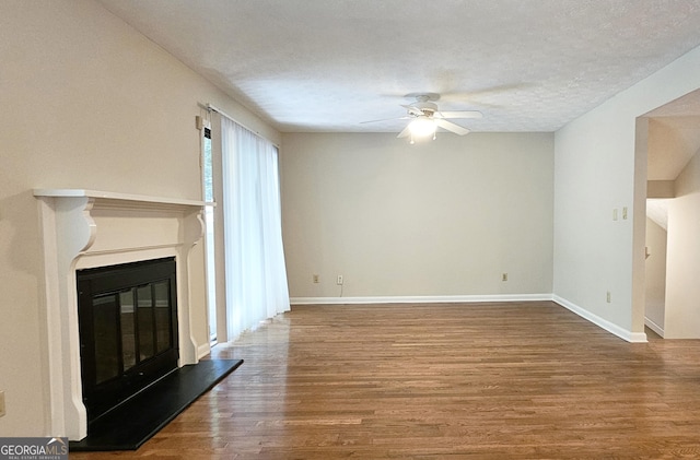 2929 Torreya Way SE, Marietta, GA 30067 - unfurnished living room featuring a ceiling fan, wood finished floors, a glass covered fireplace, baseboards, and a textured ceiling