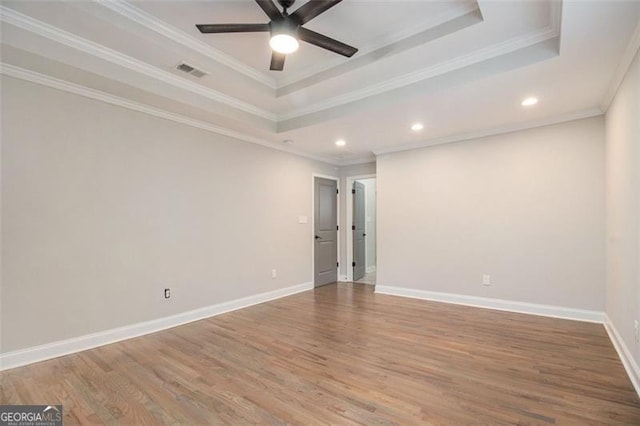 unfurnished room featuring visible vents, wood finished floors, a ceiling fan, and a raised ceiling