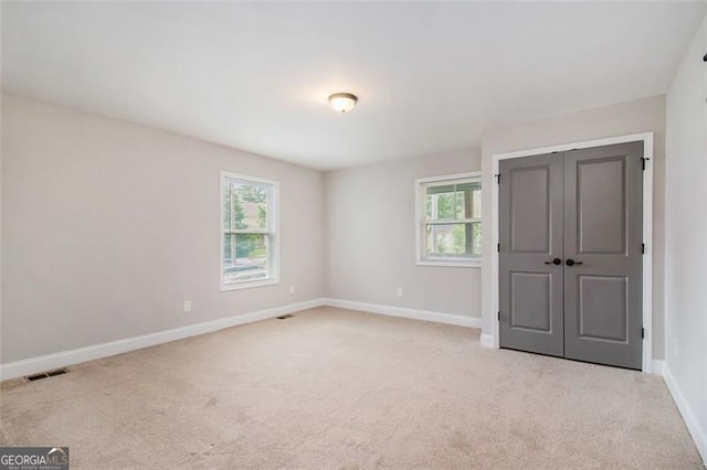 unfurnished bedroom with baseboards, carpet floors, visible vents, and a closet