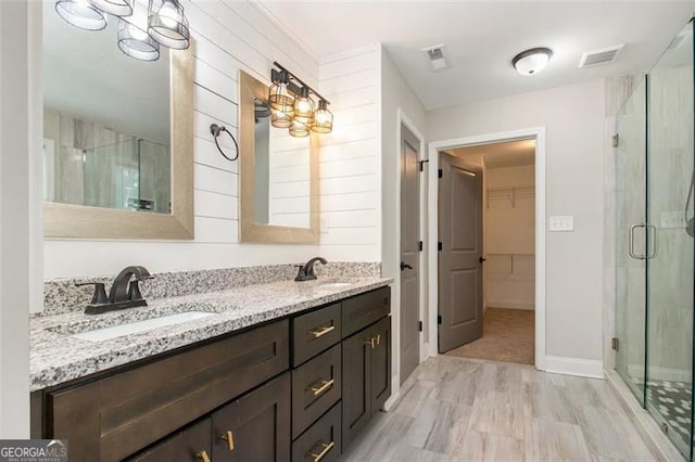 full bathroom featuring a stall shower, visible vents, a spacious closet, and a sink
