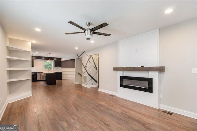 unfurnished living room featuring recessed lighting, a sink, visible vents, a ceiling fan, and wood finished floors