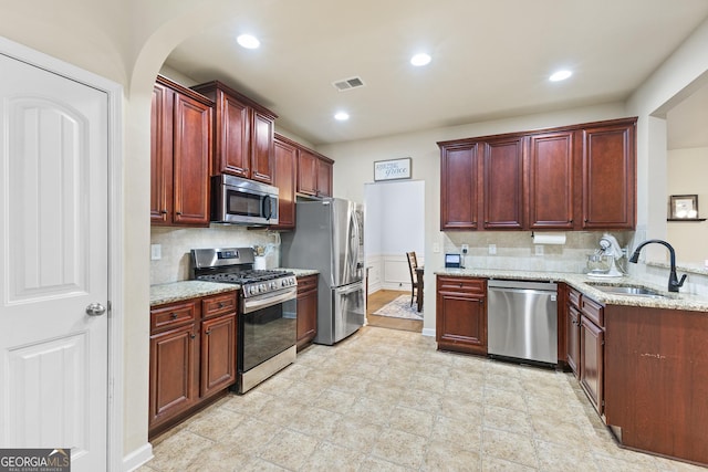 6018 Cloverfield Way, Braselton, GA 30517 - kitchen featuring stainless steel appliances, a sink, dark brown cabinets, light stone countertops, and arched walkways