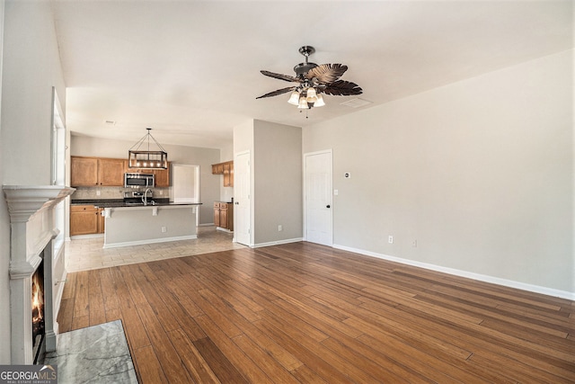3707 Mcguire St NW, Kennesaw, GA 30144 - unfurnished living room with ceiling fan, wood-type flooring, baseboards, a fireplace with flush hearth, and a sink