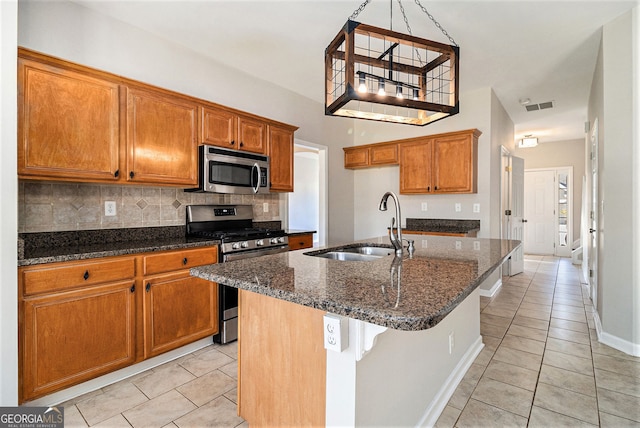 3707 Mcguire St NW, Kennesaw, GA 30144 - kitchen with stainless steel appliances, a sink, light tile patterned flooring, and brown cabinets