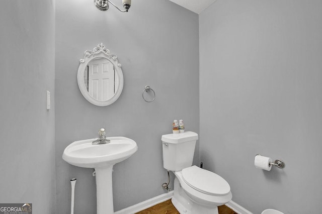 half bathroom with baseboards and toilet