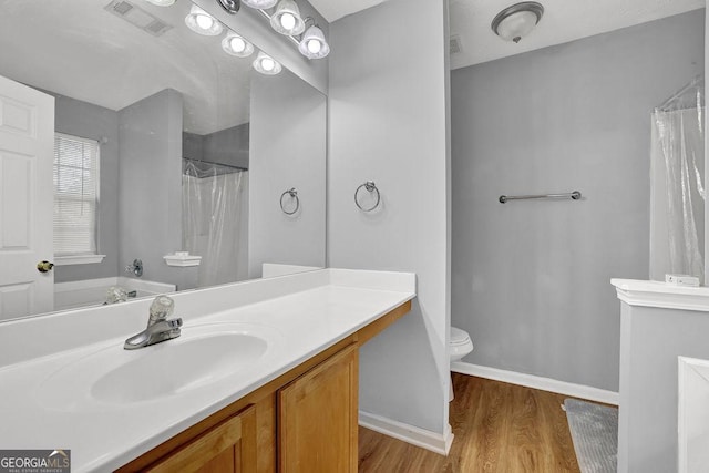bathroom featuring vanity, toilet, baseboards, visible vents, and wood finished floors