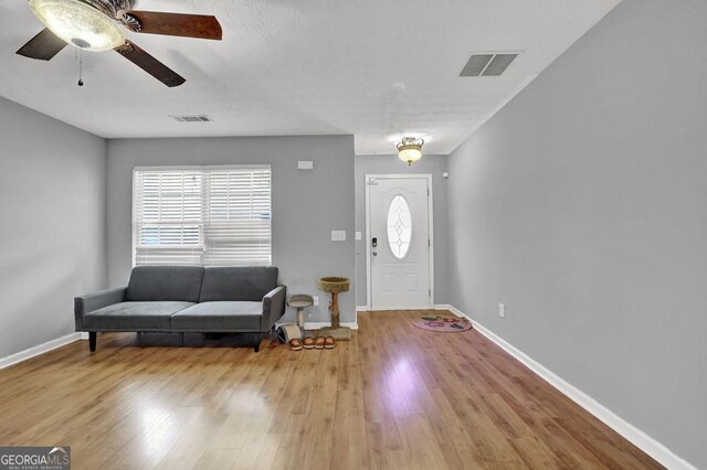 foyer featuring baseboards, visible vents, wood finished floors, and a ceiling fan