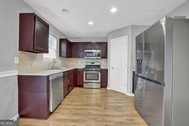 kitchen featuring decorative backsplash, light wood finished floors, a sink, and appliances with stainless steel finishes