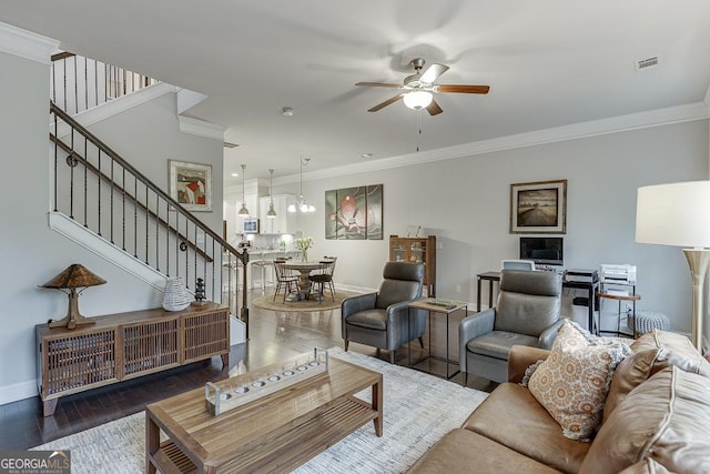 living room with ceiling fan, stairway, baseboards, crown molding, and wood finished floors