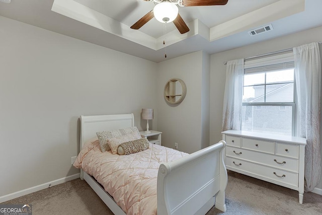 bedroom featuring a raised ceiling, carpet, baseboards, and ceiling fan