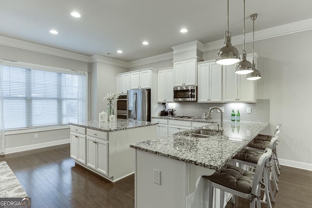 kitchen featuring appliances with stainless steel finishes, a sink, baseboards, a center island, and white cabinets