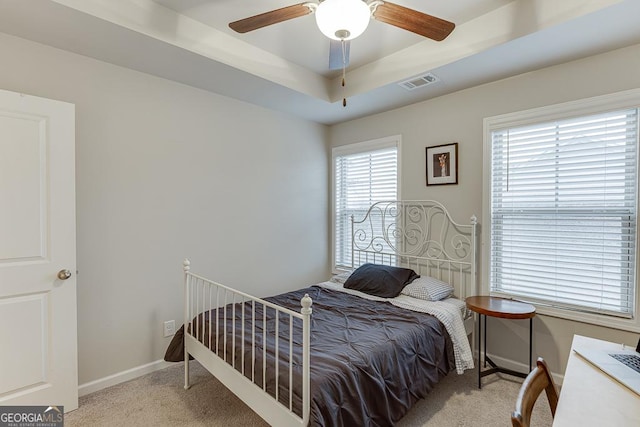 carpeted bedroom with baseboards, a raised ceiling, and ceiling fan