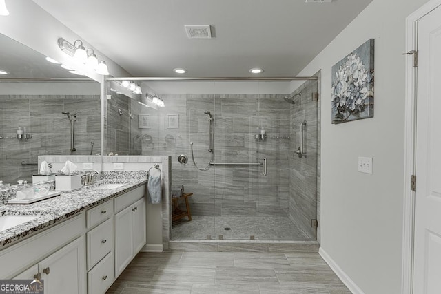 bathroom with recessed lighting, a shower stall, double vanity, and baseboards