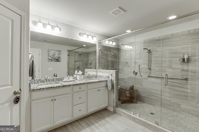 bathroom with a shower stall, double vanity, and recessed lighting