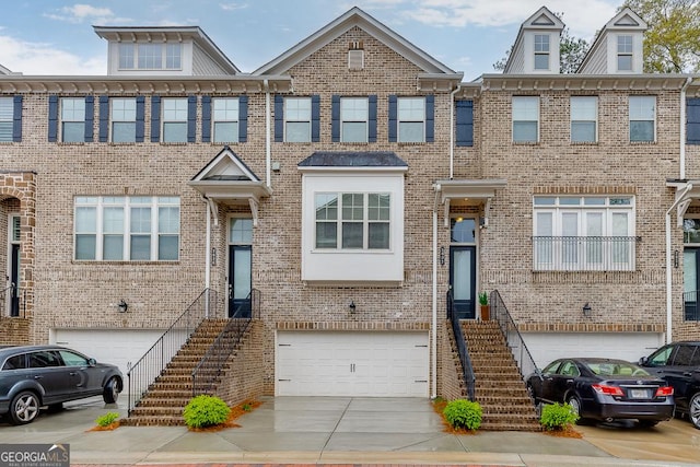 multi unit property with a garage, brick siding, and driveway