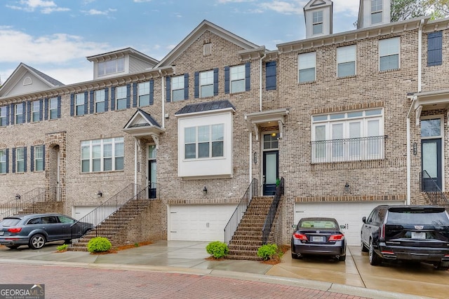 multi unit property featuring driveway, stairs, brick siding, and an attached garage