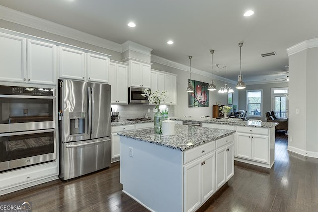 kitchen featuring stainless steel appliances, a peninsula, a center island, dark wood-style flooring, and white cabinets