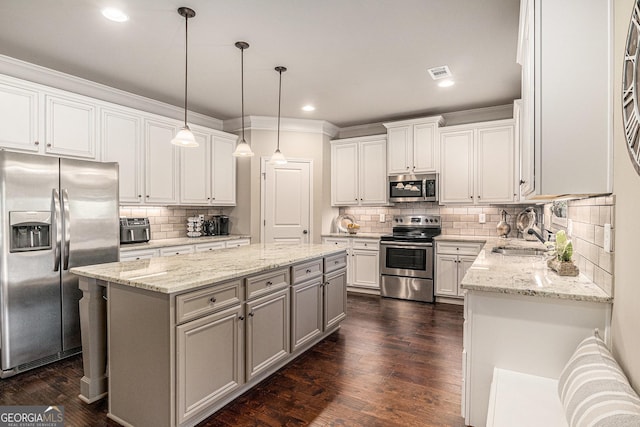 kitchen featuring a sink, a center island, crown molding, backsplash, and appliances with stainless steel finishes
