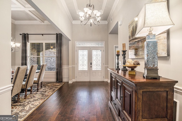 entryway with dark wood-type flooring, a chandelier, crown molding, and a high ceiling