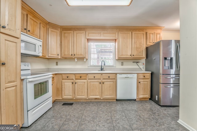 kitchen featuring light countertops, white appliances, light brown cabinetry, a sink, and light tile patterned flooring