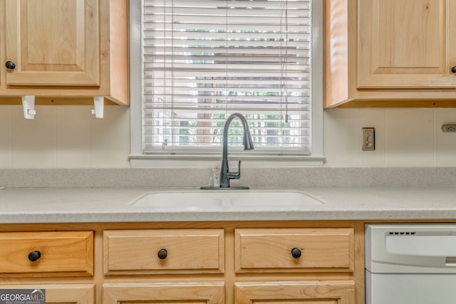 kitchen featuring a sink, white dishwasher, and light brown cabinetry