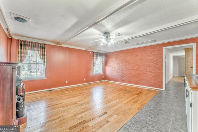 unfurnished room featuring a ceiling fan, light wood-style floors, brick wall, and a textured ceiling