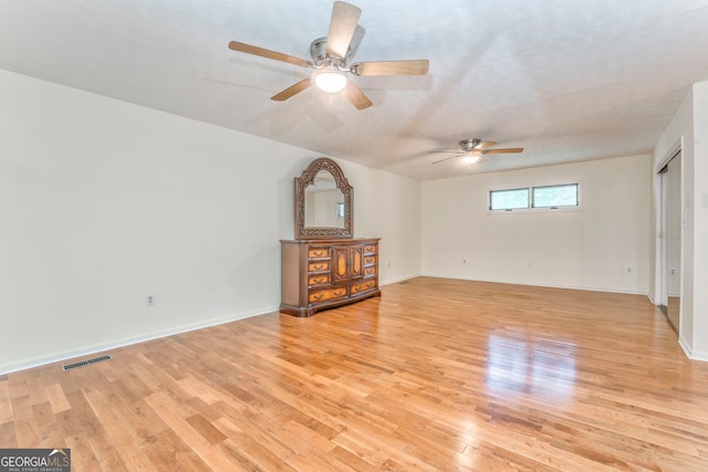 interior space with a ceiling fan, baseboards, light wood-style floors, and visible vents