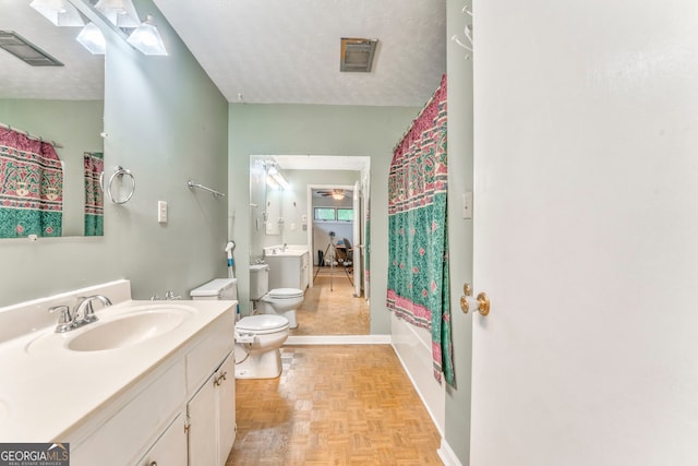 full bath featuring vanity, toilet, baseboards, a textured ceiling, and visible vents
