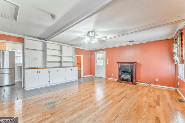unfurnished living room featuring baseboards, a textured ceiling, visible vents, light wood-style flooring, and ceiling fan