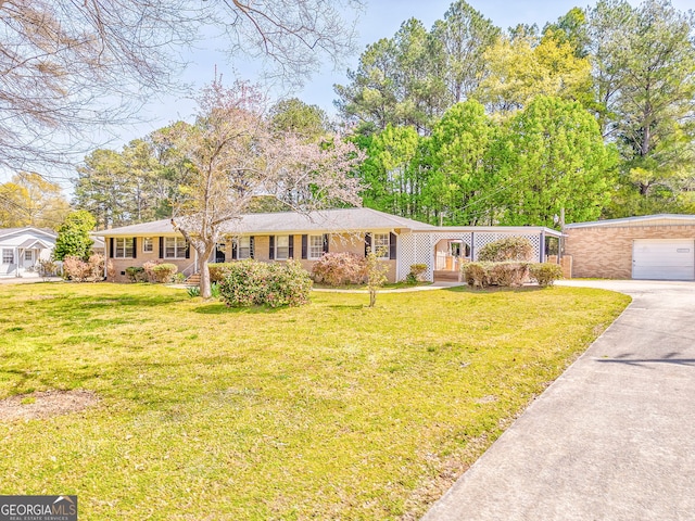 ranch-style house with driveway, a front yard, and a detached garage