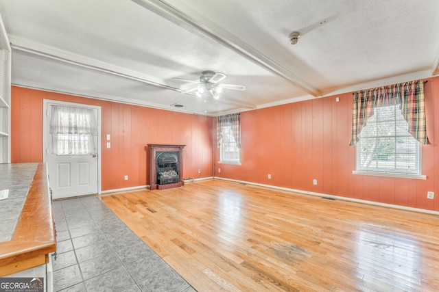 unfurnished living room featuring visible vents, light wood-style flooring, a ceiling fan, and beam ceiling