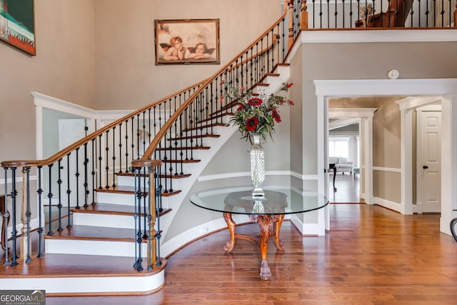 staircase with baseboards, a high ceiling, and wood finished floors