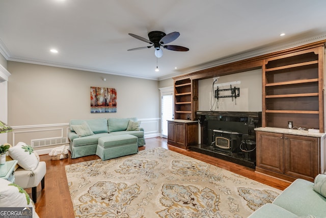 living room featuring crown molding, wood finished floors, ceiling fan, and visible vents